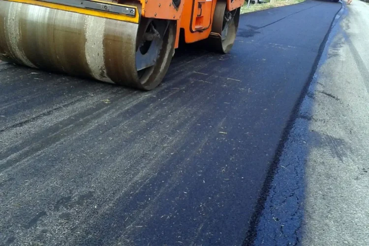 Rullo compressore stende asfalto fresco su una strada durante lavori di manutenzione stradale
