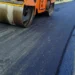 Rullo compressore stende asfalto fresco su una strada durante lavori di manutenzione stradale