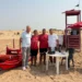 Quattro persone davanti alla torretta di salvataggio e al pattino rosso su una spiaggia di Donnalucata, a Scicli.