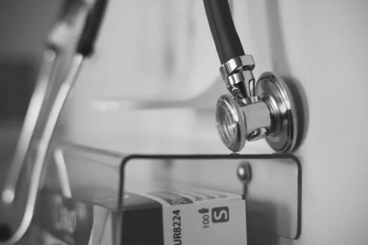 Uno stetoscopio appeso a una parete accanto a una scatola di guanti monouso, in un ambulatorio medico