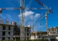 Gru e impalcature su un cantiere edile con cielo azzurro sullo sfondo, lavori di costruzione in corso
