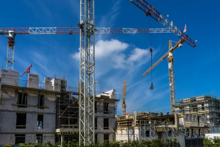 Gru e impalcature su un cantiere edile con cielo azzurro sullo sfondo, lavori di costruzione in corso