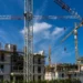 Gru e impalcature su un cantiere edile con cielo azzurro sullo sfondo, lavori di costruzione in corso