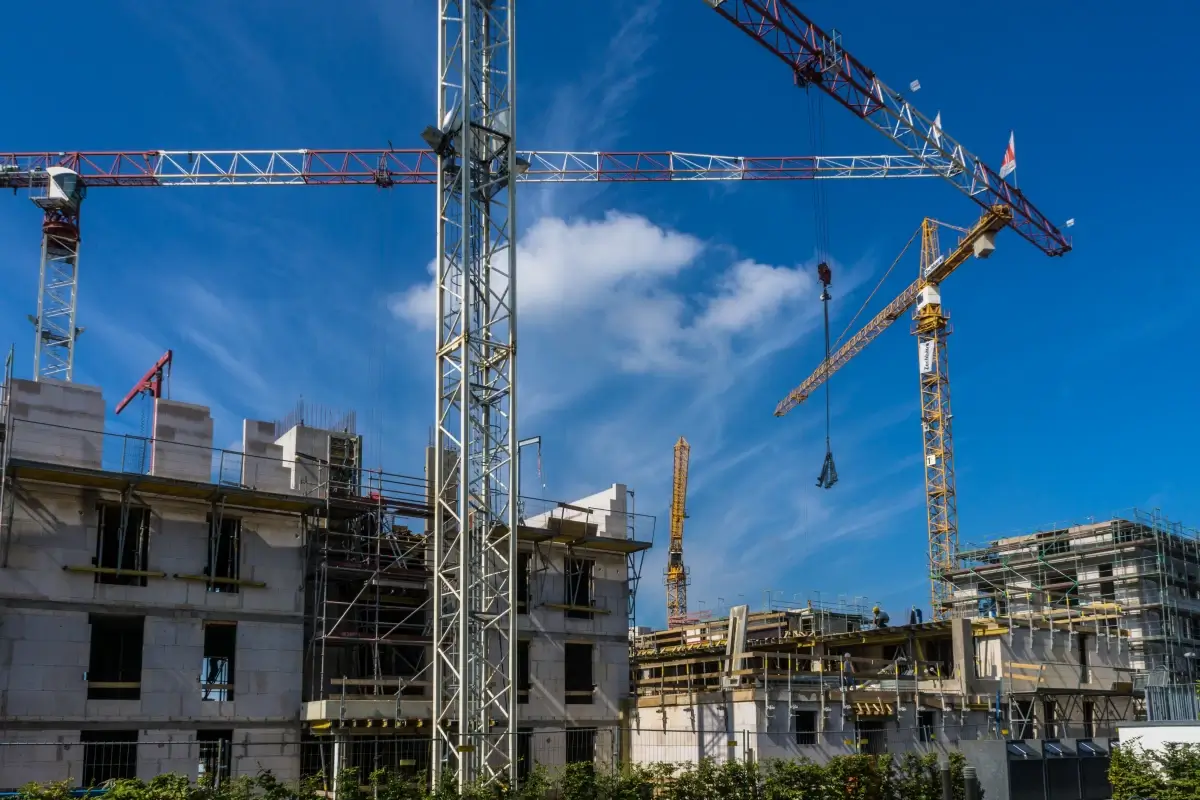 Gru e impalcature su un cantiere edile con cielo azzurro sullo sfondo, lavori di costruzione in corso