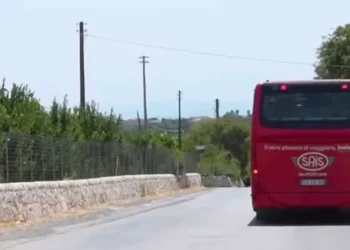 Autobus rosso SAIS Autolinee di spalle su strada di campagna con muretti a secco, diretto verso Marina di Modica
