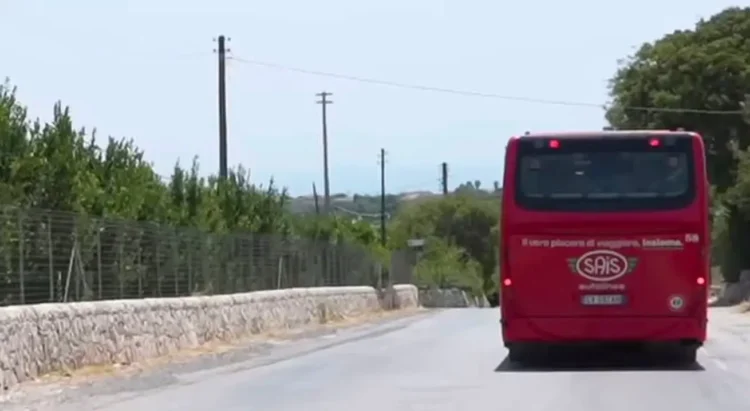Autobus rosso SAIS Autolinee di spalle su strada di campagna con muretti a secco, diretto verso Marina di Modica