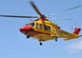 Elicottero del 118 giallo e rosso in volo su cielo azzurro, impiegato per il trasporto di un paziente in emergenza