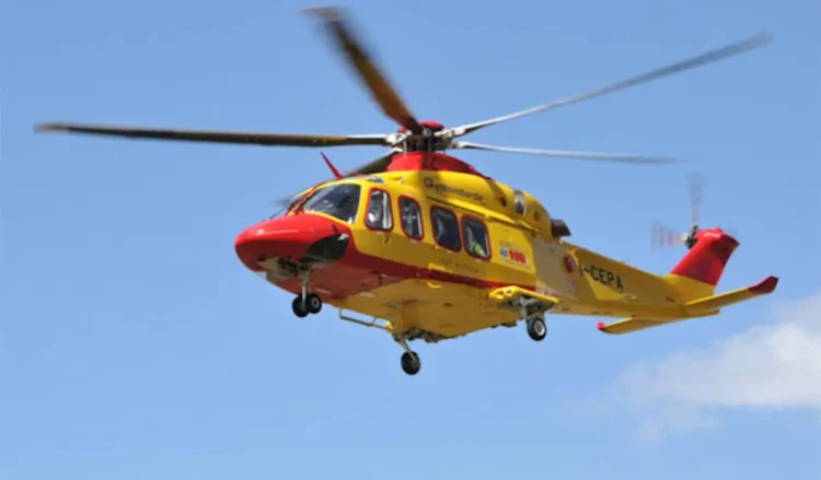Elicottero del 118 giallo e rosso in volo su cielo azzurro, impiegato per il trasporto di un paziente in emergenza