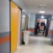 Corridoio dell'ospedale con un'ambulanza visibile all'ingresso e due persone sullo sfondo.