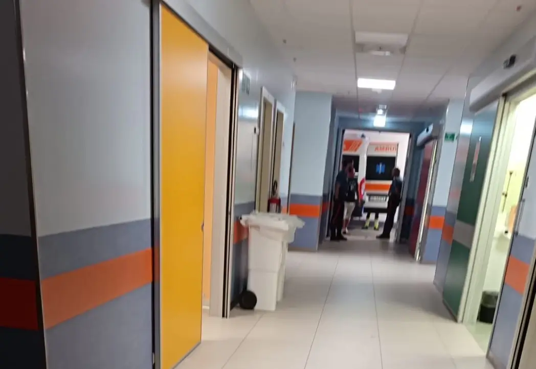 Corridoio dell'ospedale con un'ambulanza visibile all'ingresso e due persone sullo sfondo.