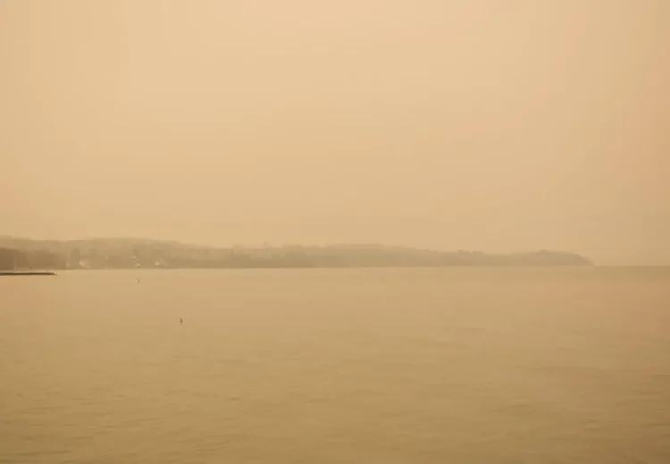Cielo e mare avvolti da una foschia arancione di polvere sahariana, con la costa a malapena visibile all'orizzonte