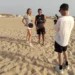 Un'inviata Rai e un istruttore con racchette da beach tennis in spiaggia a Scoglitti, ripresi da un operatore video