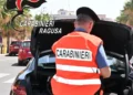 Carabiniere in gilet arancione ispeziona il bagagliaio di un'auto durante un controllo stradale