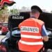 Carabiniere in gilet arancione ispeziona il bagagliaio di un'auto durante un controllo stradale