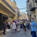 Gruppo di persone in una via del centro storico di Gangi, addobbata con nastri e spighe di grano per la festa estiva.
