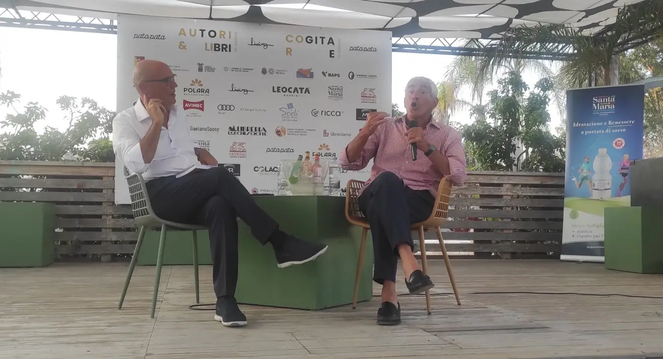 Pierferdinando Casini parla al microfono accanto a Franco Raniolo, seduti sul palco del Pata Pata di Sampieri.
