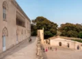 Visitatori nel cortile del Castello di Donnafugata a Ragusa, con la facciata neogotica e gli edifici rustici sullo sfondo
