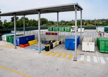 Container colorati per la raccolta differenziata disposti sotto una tettoia in un centro di raccolta rifiuti