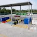 Container colorati per la raccolta differenziata disposti sotto una tettoia in un centro di raccolta rifiuti