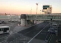Pista dell'aeroporto di Catania-Fontanarossa con torre di controllo, aerei e passerella d'imbarco al tramonto