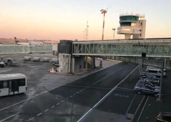 Pista dell'aeroporto di Catania-Fontanarossa con torre di controllo, aerei e passerella d'imbarco al tramonto