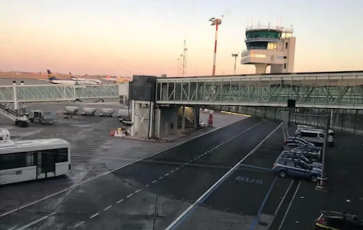 Pista dell'aeroporto di Catania-Fontanarossa con torre di controllo, aerei e passerella d'imbarco al tramonto