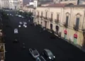 Strada del versante etneo ricoperta di cenere vulcanica scura, vista dall'alto, con auto in transito