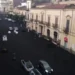 Strada del versante etneo ricoperta di cenere vulcanica scura, vista dall'alto, con auto in transito