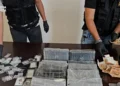 Panetti di cocaina avvolti in cellophane su un tavolo, affiancati da due kit narcotest Multi-Drug Test Panel e banconote in euro