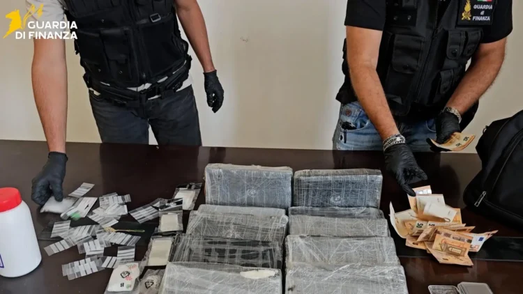 Panetti di cocaina avvolti in cellophane su un tavolo, affiancati da due kit narcotest Multi-Drug Test Panel e banconote in euro