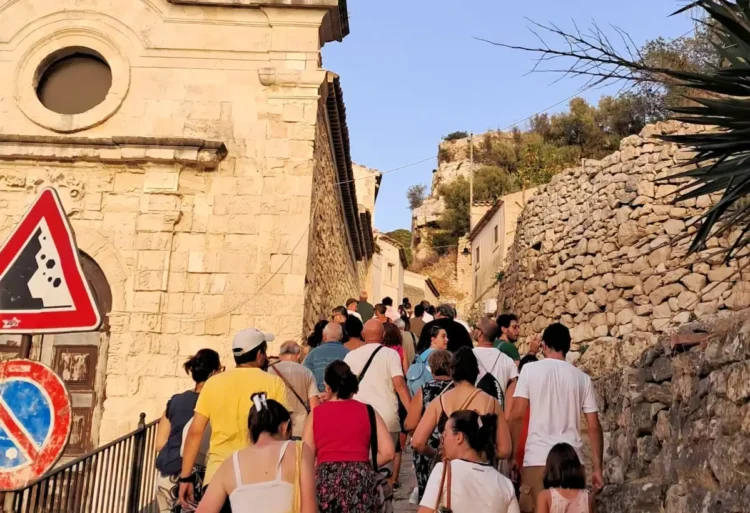 Un gruppo di persone risale una stradina in pietra durante la visita guidata sul Colle di San Matteo a Scicli