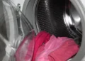 Interno di una lavatrice a carica frontale con capi rosa nel cestello