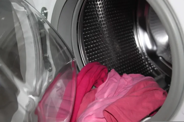 Interno di una lavatrice a carica frontale con capi rosa nel cestello