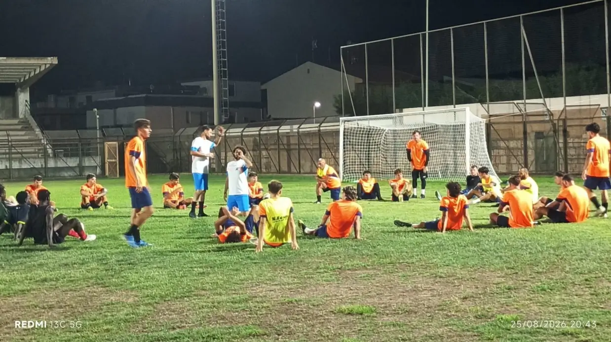 Giocatori del Comiso seduti in cerchio sul campo dello stadio comunale durante l'allenamento serale precampionato