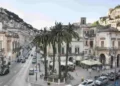 Corso Umberto I nel centro storico di Modica, tra palme, palazzi storici e il colle della Rocca sullo sfondo
