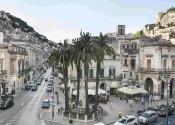 Corso Umberto I nel centro storico di Modica, tra palme, palazzi storici e il colle della Rocca sullo sfondo