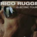 Primo piano di Enrico Ruggeri con occhiali da sole, locandina con scritta Electric Tour 2026.