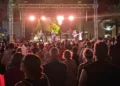 Il pubblico segue dal basso il concerto della band sul palco allestito in piazza, tra luci sceniche e palme.
