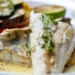 Filetto di pesce bianco grigliato con verdure di contorno e una fetta di lime, servito con salsa al burro e timo