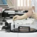 Mano guantata di un operatore sanitario preleva una provetta di sangue da un analizzatore automatico da laboratorio.