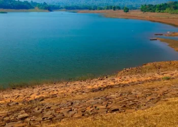 Invaso artificiale con livello d'acqua basso e ampie sponde rocciose asciutte a vista, torre di presa sul lato destro