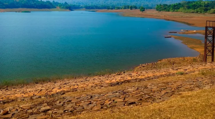Invaso artificiale con livello d'acqua basso e ampie sponde rocciose asciutte a vista, torre di presa sul lato destro