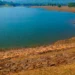 Invaso artificiale con livello d'acqua basso e ampie sponde rocciose asciutte a vista, torre di presa sul lato destro