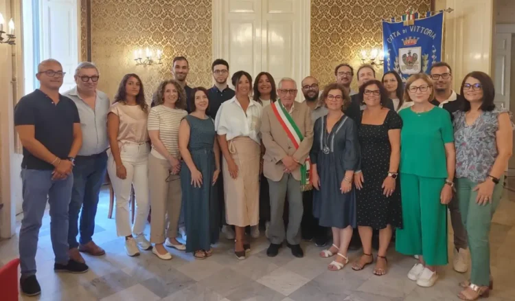 Gruppo di circa venti persone in posa nella Sala degli Specchi di Palazzo Iacono a Vittoria, con fascia tricolore e gonfalone del Comune