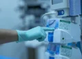 Mano guantata indica un dispositivo medico ospedaliero con etichette di manutenzione e calibrazione