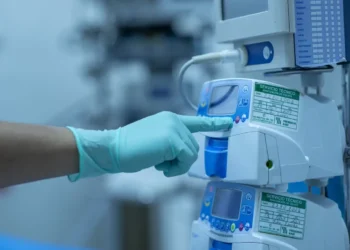 Mano guantata indica un dispositivo medico ospedaliero con etichette di manutenzione e calibrazione