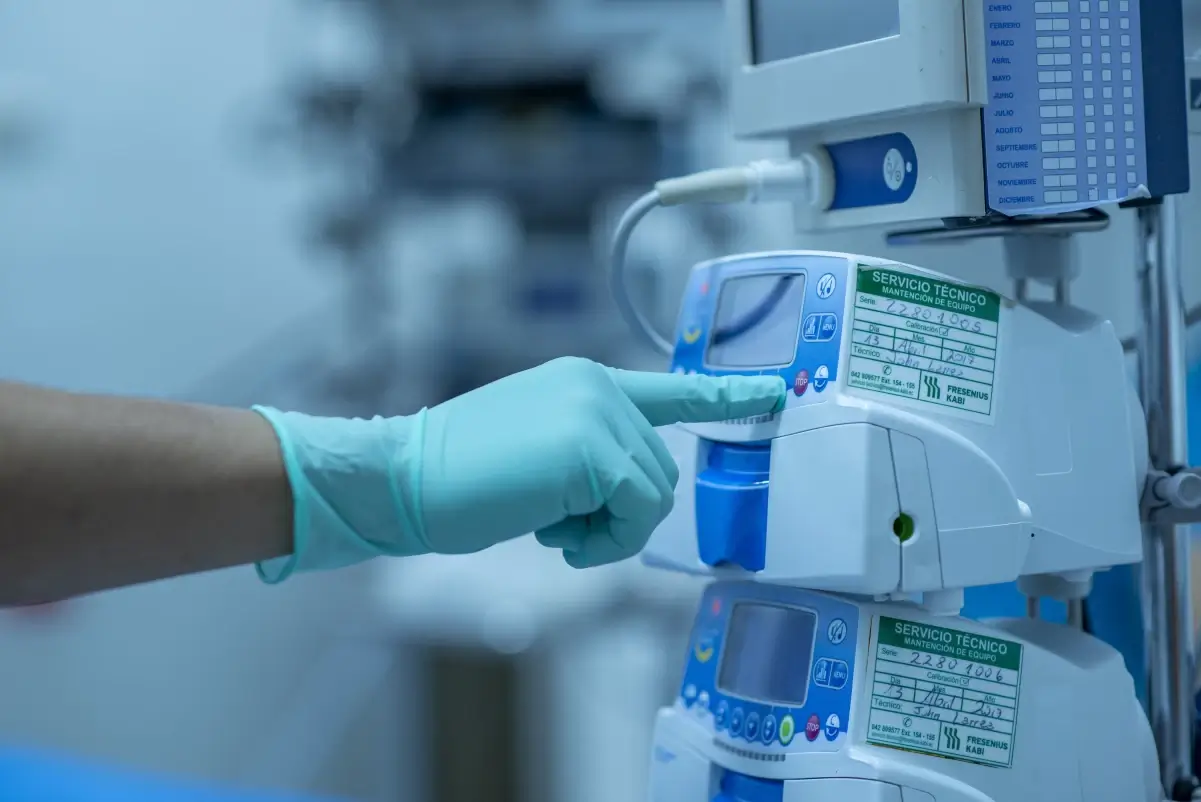 Mano guantata indica un dispositivo medico ospedaliero con etichette di manutenzione e calibrazione