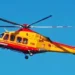 Elicottero del 118 in volo su cielo azzurro, livrea giallo-rossa, impegnato in un intervento di soccorso sanitario.