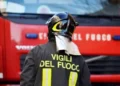 Vigili del fuoco di spalle davanti a un mezzo antincendio durante un intervento