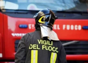 Vigili del fuoco di spalle davanti a un mezzo antincendio durante un intervento